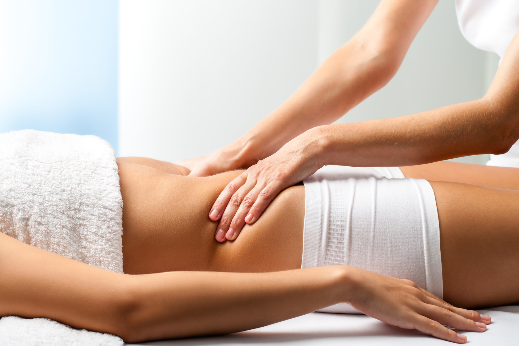 Close up of osteopath doing manipulative abdomen massage on female patient.